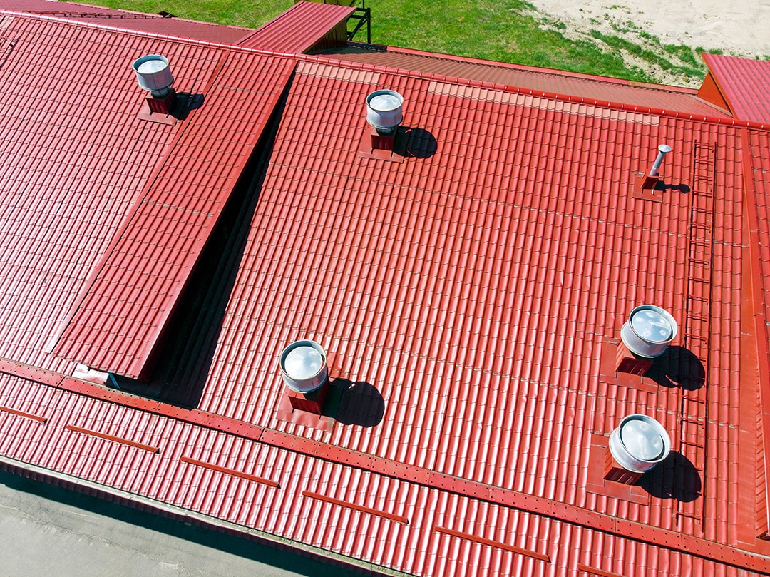 new red metal warehouse roof with installed pipes of ventilation